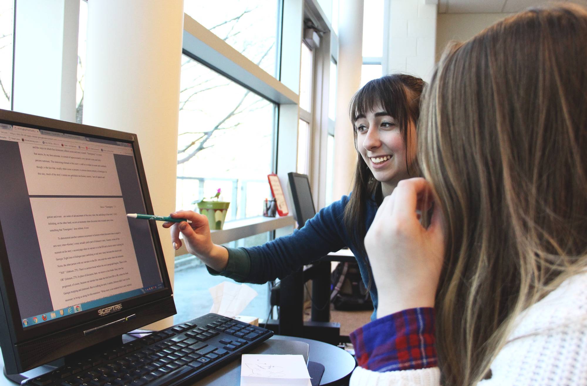A student and a writing consultant working together at a computer